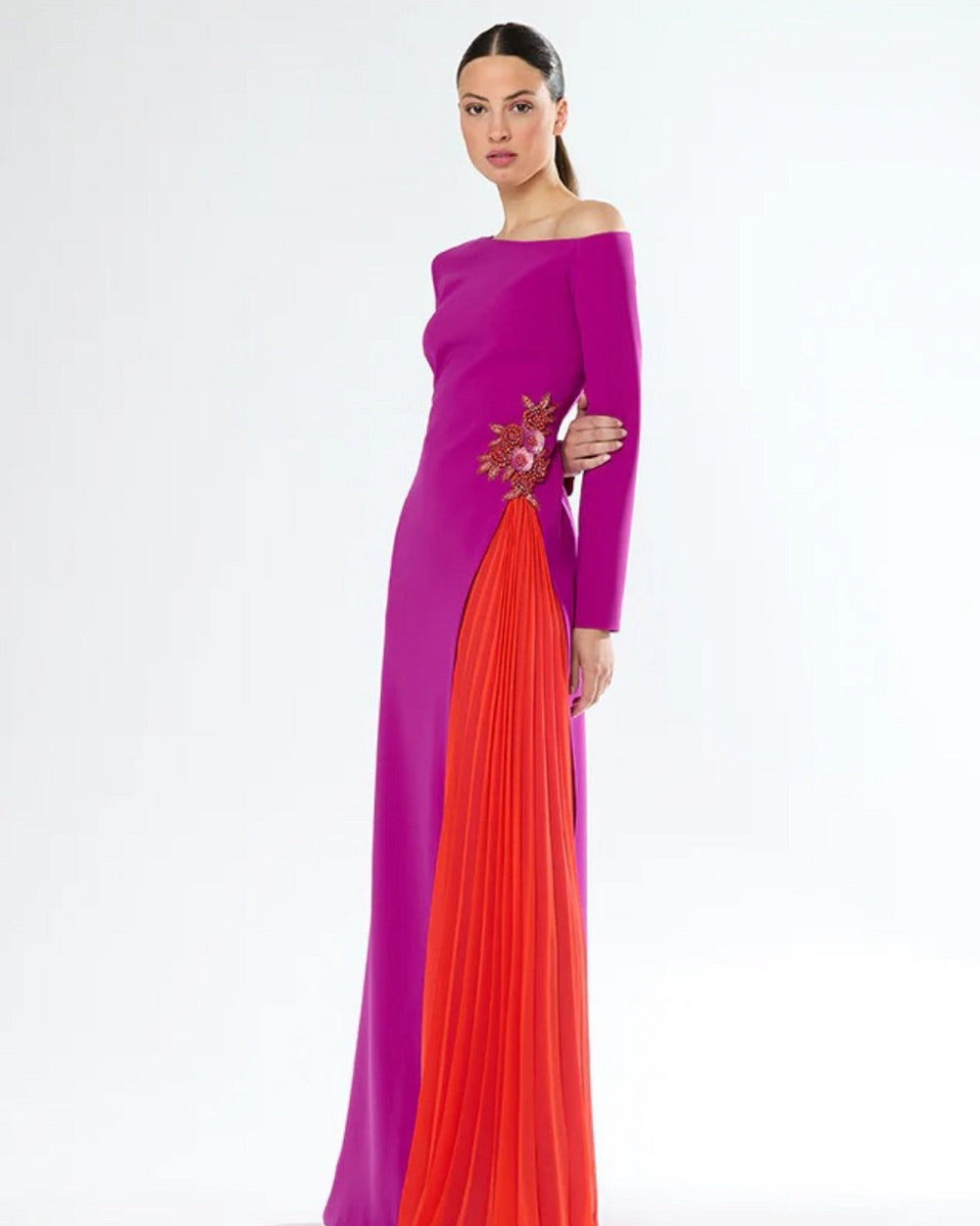 Tara, a magenta gown with a bold coral contrast panel, an off the shoulder neckline and long sleeves.