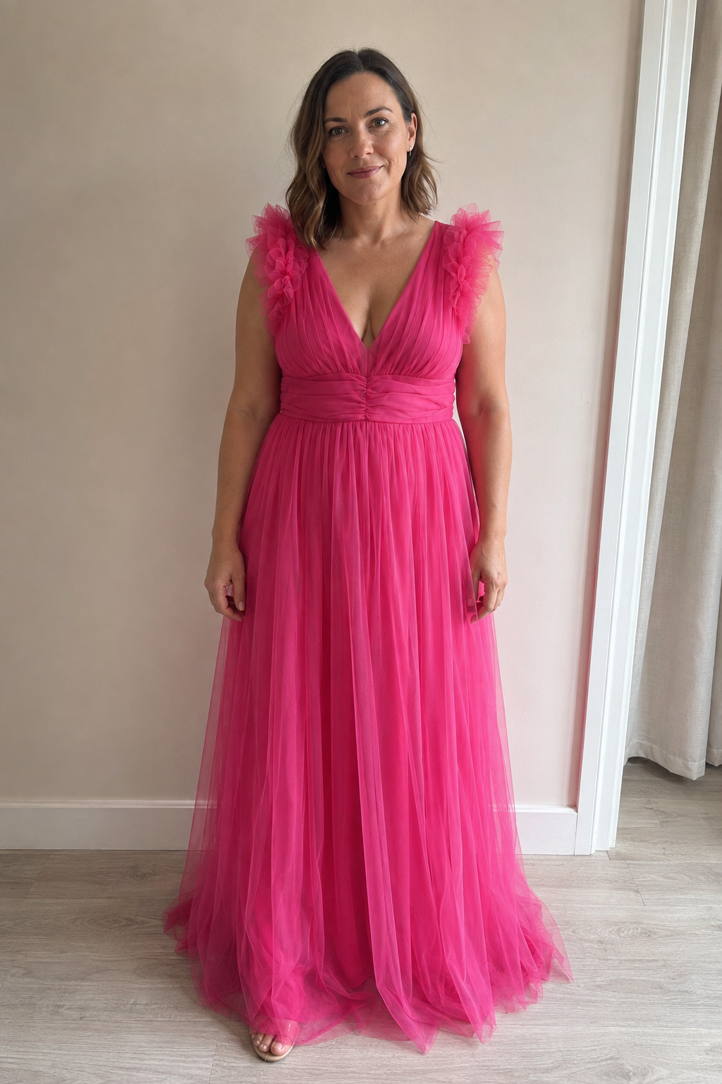 Amara, a hot pink tulle gown with a deep V neckline, a gathered bodice and ruffles of tulle at the shoulders.