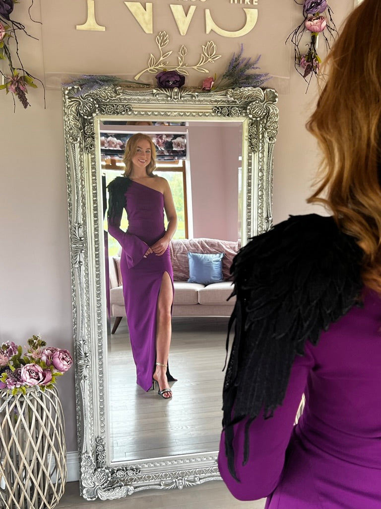 Willow, a vibrant purple full length dress with one shoulder and a single full sleeve that opens at the cuff.