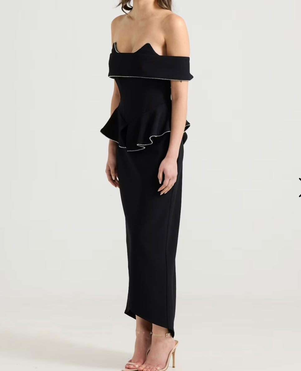 Sydney, a black corseted gown in bonded crepe with a sculptural off the shoulder panel and a peplum at the waist.