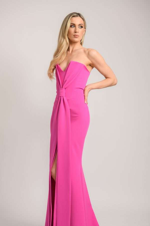Verity, a hot pink crepe gown with a strapless V notch bodice and a folded drape gathered at one side of the waist.